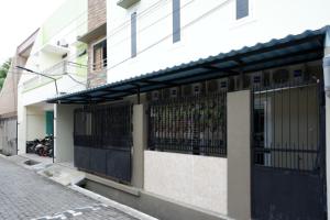 三宝垄RedDoorz Hostel near Kota Lama Semarang的街道上一座白色的建筑,有黑色的大门