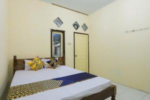 BlimbingsariOYO 2371 Islami Family Residence的一间卧室配有黄色和蓝色枕头的床