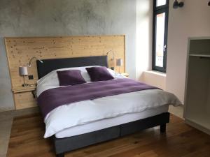 Les Hauts-GeneveysLe Manoir de l'Oselière & Spa的一间卧室配有一张大床,铺有紫色和白色的床单。