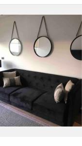 圣地亚哥Clínica Las Condes, espectacular departamento nuevo 80 m2的客厅配有黑色沙发和两面镜子