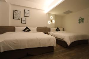 花莲市微停宿旅的一间卧室配有两张带白色床单的床