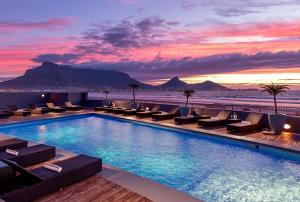 开普敦泻湖滩酒店及Spa的一个带椅子的酒店游泳池,日落