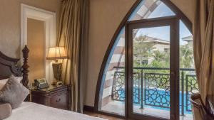 迪拜Zabeel Saray Royal Residences Lagoon Villa的卧室设有通往阳台的大玻璃门