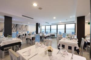 坎帕斯蒂利亚诺蒂卡酒店的餐厅设有白色的桌椅和窗户。