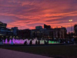 曼彻斯特QuickSpaces Heart of the City的一群人坐在喷泉旁,日落时分