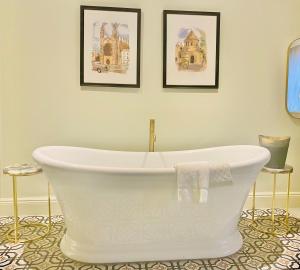 剑桥Gonville Hotel的浴室设有白色浴缸,墙上挂有两张照片