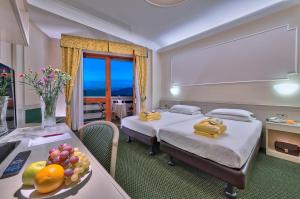 蒙特格罗托泰梅安东尼亚诺温泉酒店的酒店客房设有两张床和一张带果盘的桌子。