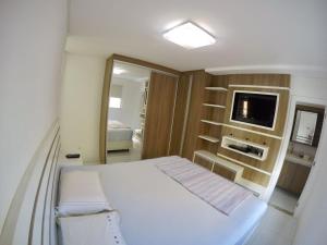 巴拉奈里奥-坎布里乌Apto alto padrão的卧室配有白色的床和电视。
