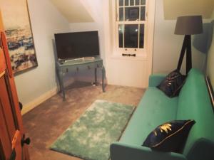 波特拉什The Carrick的客厅配有绿色沙发和电视