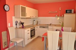 马林费尔德Ferienhaus Müritzsonne / EG-Appartement的厨房设有红色的墙壁和桌椅
