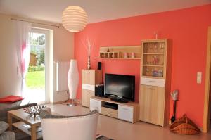 马林费尔德Ferienhaus Müritzsonne / EG-Appartement的客厅设有橙色墙壁和平面电视。