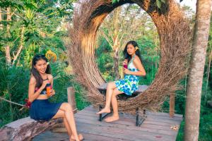 TampaksiringMirah Guest House的两个年轻的女人坐在柳条拱的长凳上