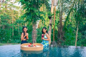 TampaksiringMirah Guest House的两个女人站在游泳池附近的水里