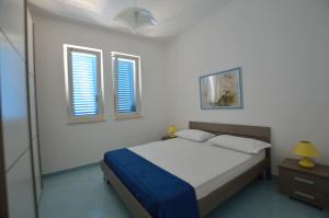 托雷瓦多Holiday Apartments Azzurro Salento的一间卧室设有一张床和两个窗户。