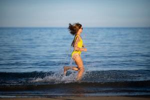 阿布达巴Three Corners Equinox Beach Resort的一名在海滩上水中跑步的女人