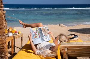 考拉亚湾Three Corners Sea Beach Resort的躺在海滩上看报纸的女人