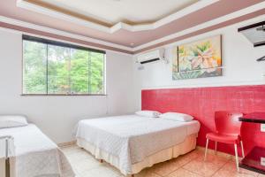 韦斯帕夏诺Ouro Hotel的一间卧室设有两张床、一张桌子和一个窗口。