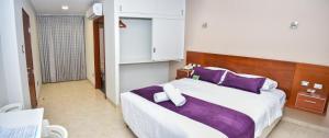齐克拉约肃内克酒店的一间卧室配有一张带紫色枕头的大床