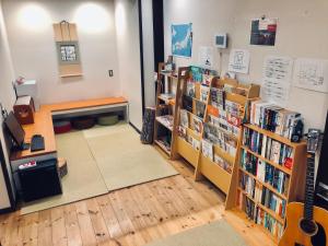 京都ゲストハウス栞庵的书架上藏书的图书馆和吉他