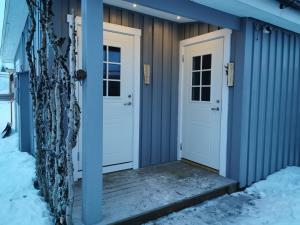 基律纳北极美食山林小屋的雪中带白色门的蓝色房子