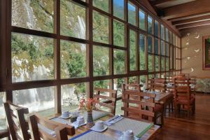 马丘比丘卡萨得索尔麦池皮池酒店的用餐室配有桌椅和大窗户