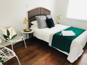 茶园Tea Gardens Hotel的一间卧室配有一张带绿毯的床和一把椅子