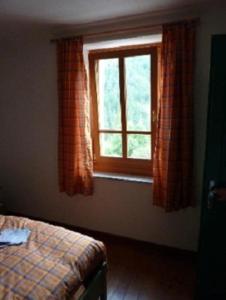 Prato Carnico克罗斯计划农家乐的一间卧室设有一张床和一个窗口