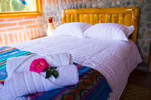 科塔卡奇Watzara Wasi Cottage Familiar Camprestre Y Lofts en Cotacachi的床上有毛巾,上面有粉红色的花