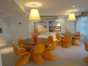 福塔莱萨Fortaleza VIP Experience的配有黄椅的房间,设有两张桌子和椅子