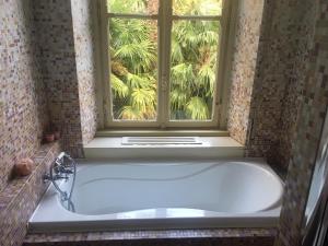 莱科天鹅别墅旅馆的带浴缸的浴室和窗户