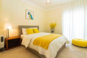 埃斯托利尔Heart of Ocean Dulpex Estoril的一间卧室配有一张带黄色枕头的床和一扇窗户