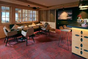 格林德尔瓦尔德Hotel Central Wolter - Grindelwald的餐厅设有酒吧,配有椅子和桌子