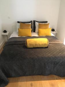 EsneuxChâteau Martin的一张大床,配有黑色毯子和黄色枕头
