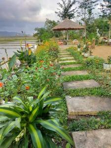 峰牙Phong Nha Rice Field Homestay的花园内种植了石材和鲜花,配有遮阳伞