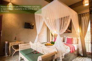 乌布艾努瓦比吉旅馆的卧室配有带白色窗帘的天蓬床