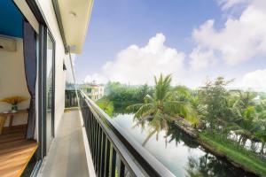 会安Ri's House Hoi An Homestay的阳台享有水景和棕榈树美景。