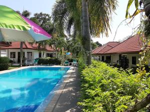 拉威海滩微笑之家酒店及泳池的一座带遮阳伞的房屋前的游泳池