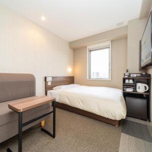 上越市Super Hotel Joetsu Myoko-Eki Nishiguchi的酒店客房配有一张床铺和一张桌子。