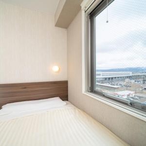 上越市Super Hotel Joetsu Myoko-Eki Nishiguchi的一间卧室设有一张床和一个大窗户