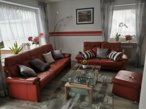 考夫博伊伦Ferienhaus CasaNoWa的客厅配有红色皮革沙发和桌子