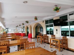 仰光格兰德桂冠酒店的餐厅设有木桌、椅子和平面电视。