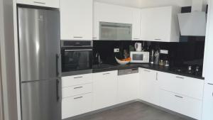 图彻皮Versi的厨房配有白色橱柜和不锈钢冰箱