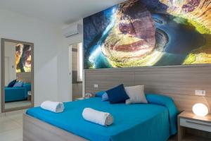 斯卡法蒂Hotel America的卧室配有蓝色的床,墙上挂着一幅大画