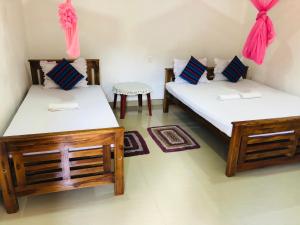 波隆纳鲁沃Kumari Guest House的一间设有两张床和一张桌子的房间