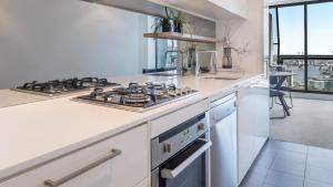 墨尔本Oaks Melbourne on William Suites的厨房配有白色的柜台和炉灶烤箱。