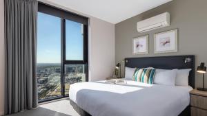 墨尔本Oaks Melbourne on William Suites的一间卧室设有一张大床和一个大窗户