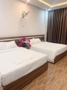 绥和市Minh Hoàng Hotel的两张位于酒店客房的床,上面有鲜花