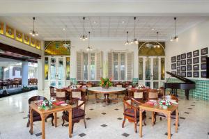 日惹The Phoenix Hotel Yogyakarta - Handwritten Collection的一间带桌椅和钢琴的餐厅