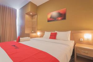 打横RedDoorz Syariah @ Villa Grand Mutiara Tasikmalaya的酒店客房设有一张带红色毯子的大床