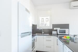 艾姆布里亚布拉瓦Apart-Rent Apartament Bahia 0015的白色的厨房配有水槽和微波炉